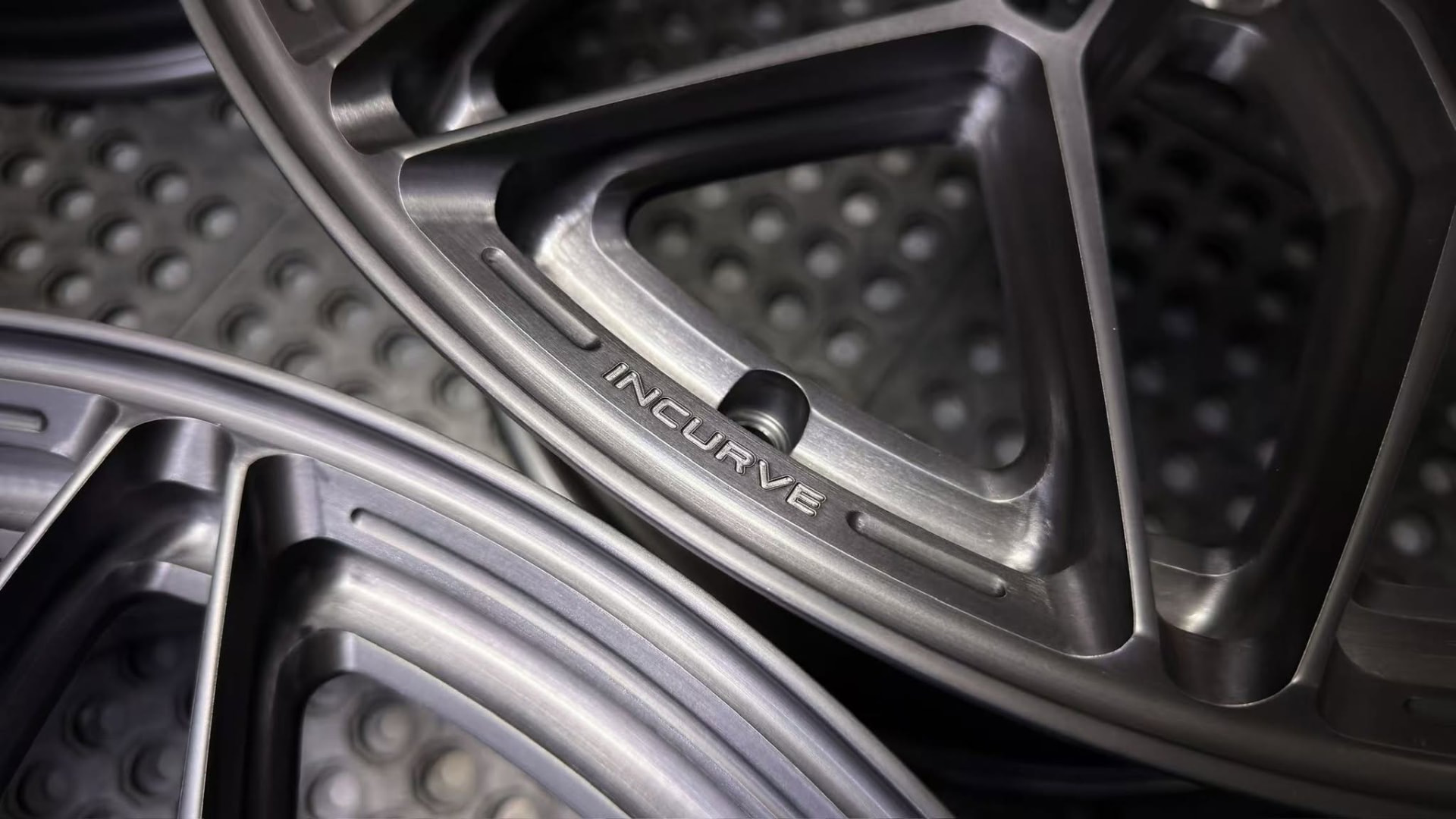 Macro detail of a brushed Incurve forged wheel spoke with engraved logo